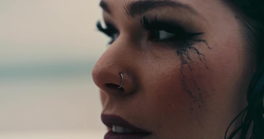 A woman is outside looking around with mascara running down her face