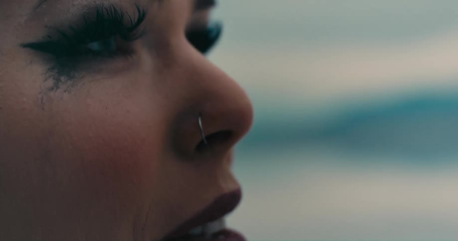 A woman with mascara smudged on her face is outside looking around