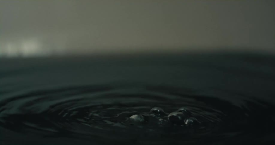 A woman in a bathtub sinks her head beneath black colored water