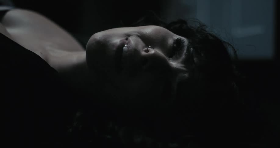 A woman is upset and laying on her back as light passes over her face