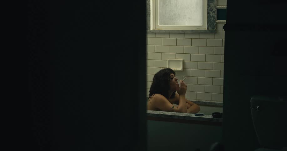 A woman who is sitting in a bathtub lights a cigarette and starts smoking