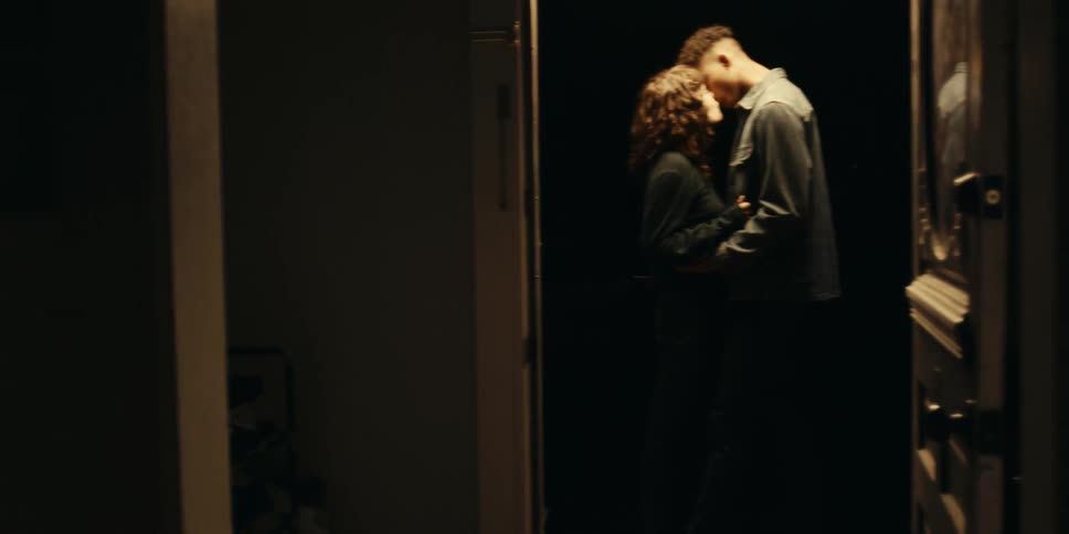 A couple is shown drinking wine kissing and cuddling in different rooms of their house