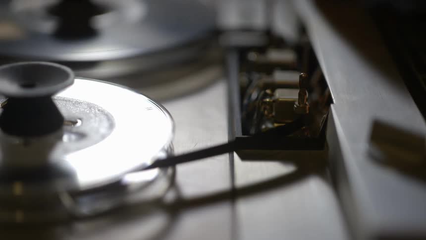 A tape machine starts spinning and is adjusted by a hand