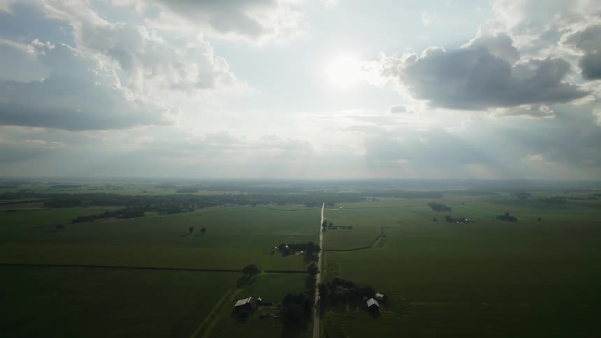 Aerial view of straight country road with sun shining on grassland