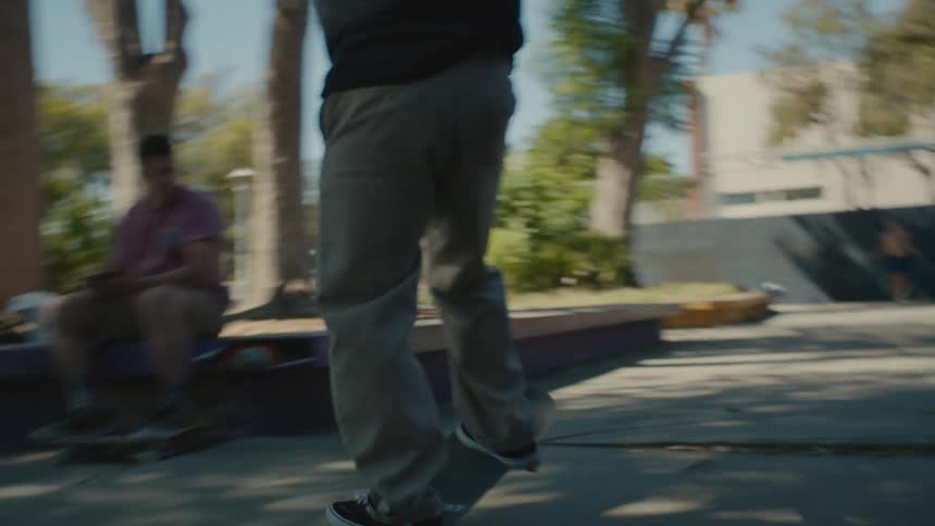 A man rides his skateboard through the park