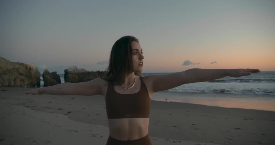 A woman is doing yoga on the beach