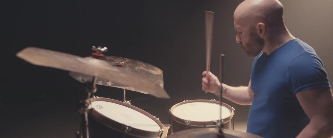 A man is holding drumsticks and playing the drums and cymbals