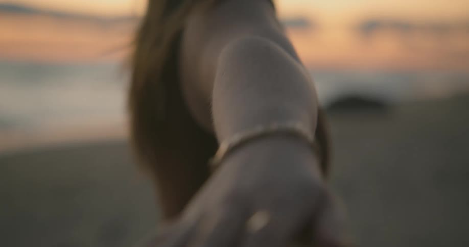 Young blonde woman holding a yoga pose on the sand beach at sunset next to the ocean