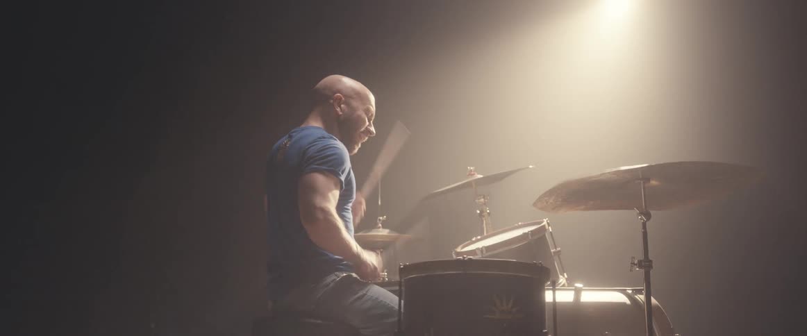 A man is playing the drums under the spotlight