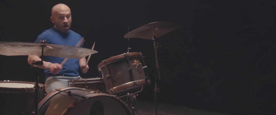 A musician is holding drumsticks and keeping the rhythm playing the drums and cymbals