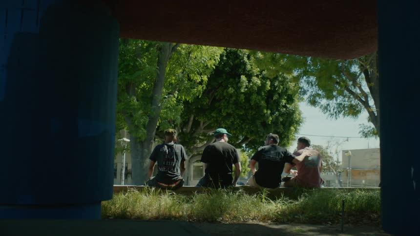 Group of friends sit on a park after skateboarding in the city at daytime