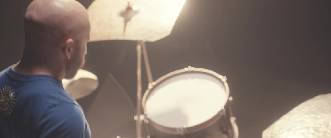 A musician is holding drumsticks and keeping the rhythm playing the drums and cymbals