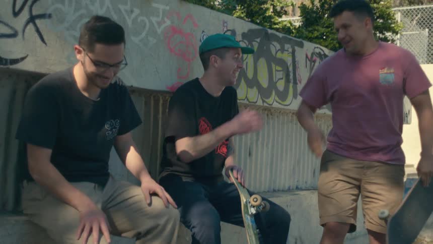 Group of skateboarders sitting on a ledge on a park in the city greet each other
