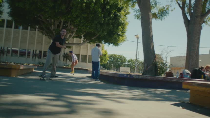 Young teen man riding a skateboard doing tricks on a park in the city at daytime