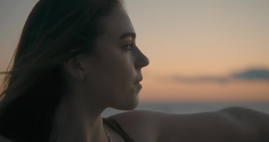 A woman is doing yoga outdoors while the sun is setting