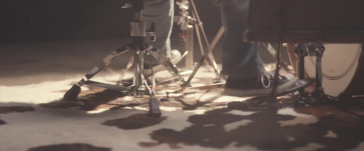 Musician manipulates foot pedals while playing drums