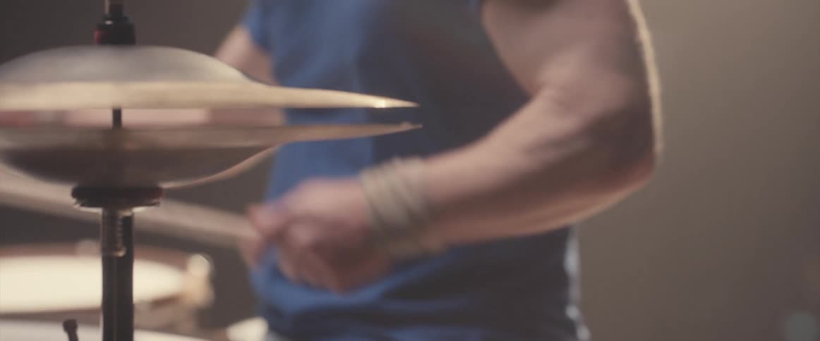 A man is holding drumsticks and playing the drums and cymbals