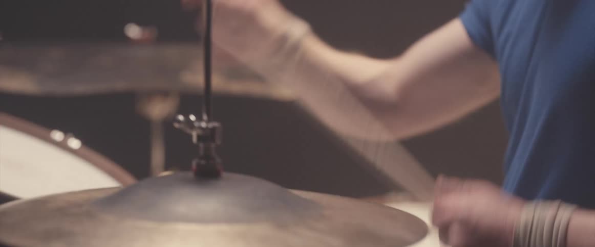 Bald muscular man playing drums on a stage under a spotlight