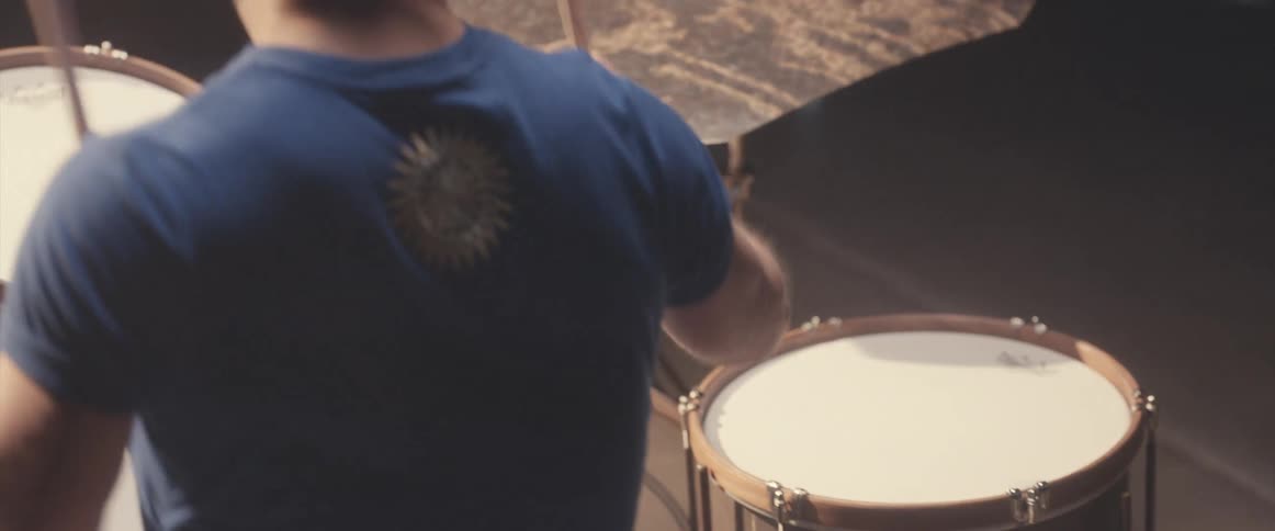 A man is holding drumsticks and playing the drums and cymbals