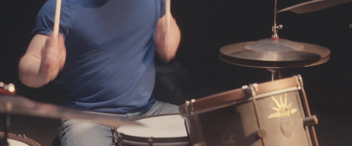 A drummer plays the drums using a pair of wooden drum sticks