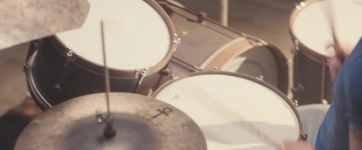 A man seems to practicing drums in a studio