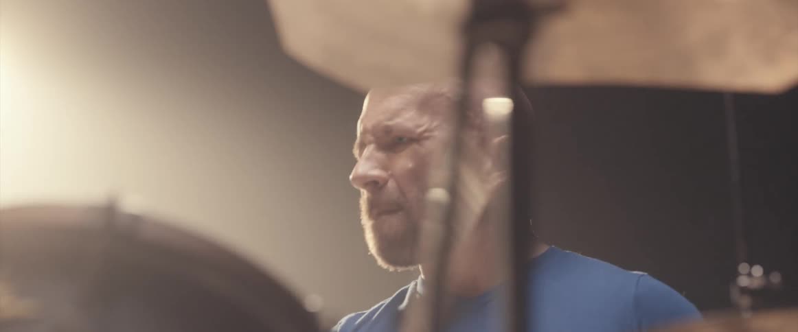 A man is playing the drums in an indoor room