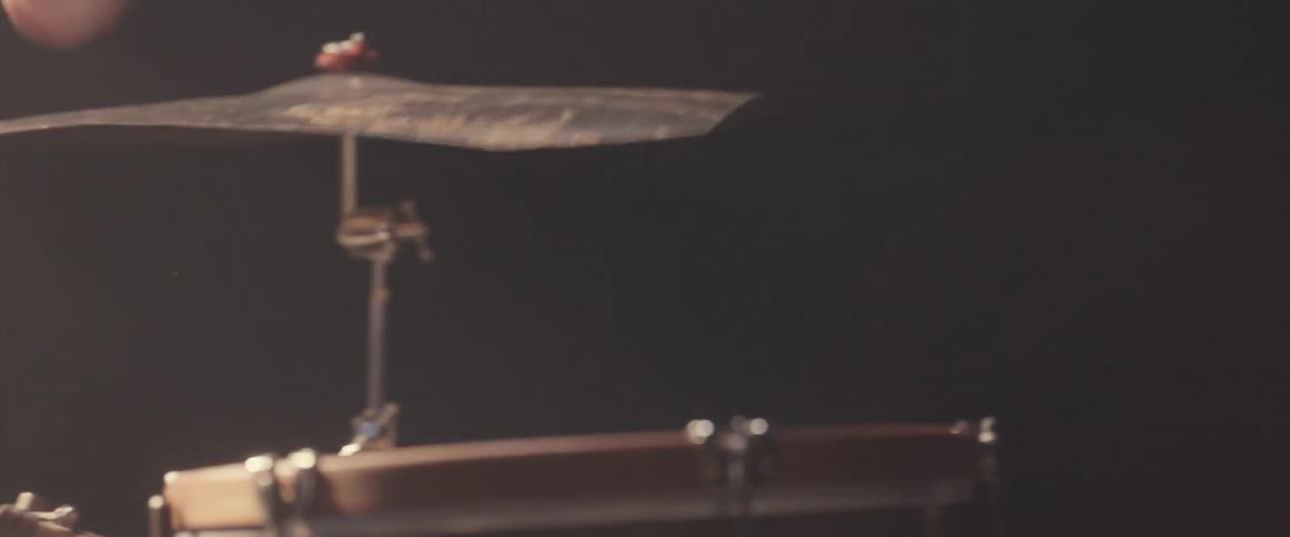 A drummer strikes a cymbal with a drum stick