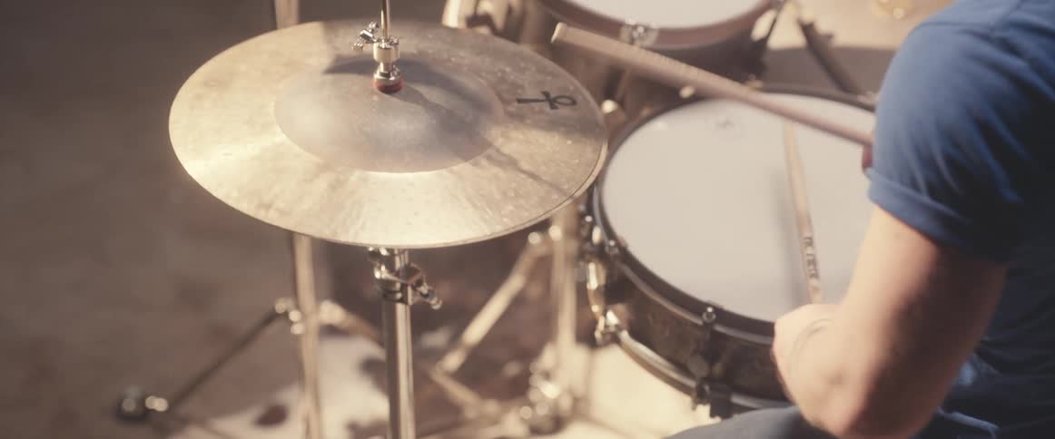 Drummer wearing t shirt plays drums that contains a cymbal with an ank on it