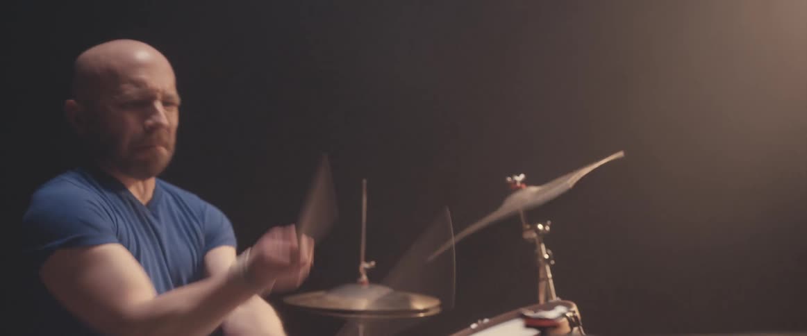 A drummer plays a drum set in a dark place