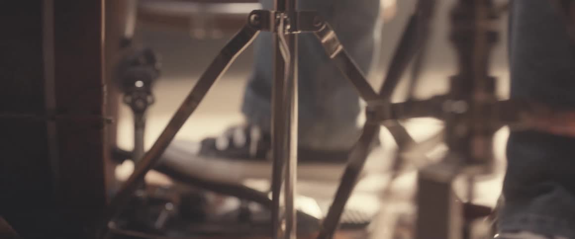 A drummers feet can be seen as they work the pedals of their drum kit in order to play the bass drum