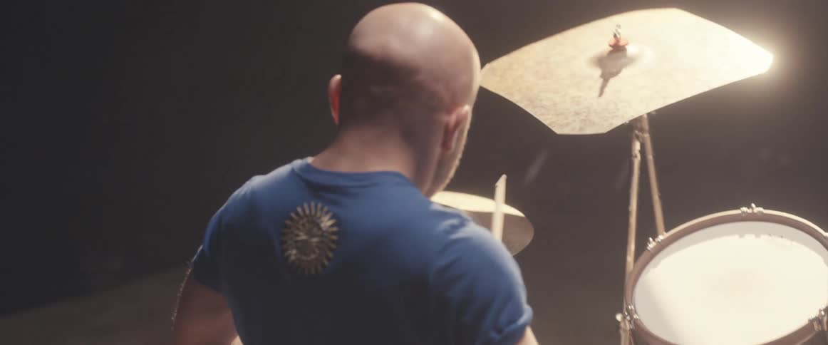 A musician is holding drumsticks and keeping the rhythm playing the drums and cymbals