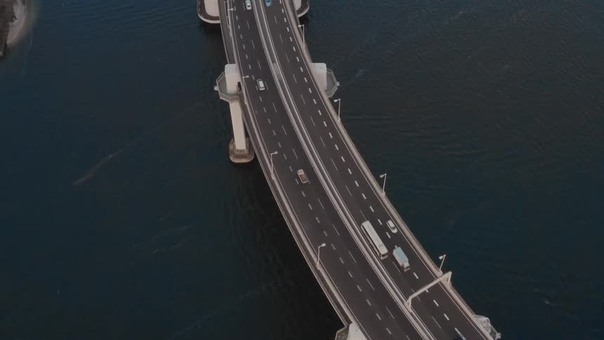 Aerial view of traffic going around the bend on a bridge over water