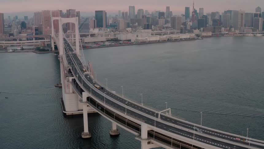 Traffic flows to and fro on to layer bridge connected to waterfront near downtown under a red sky