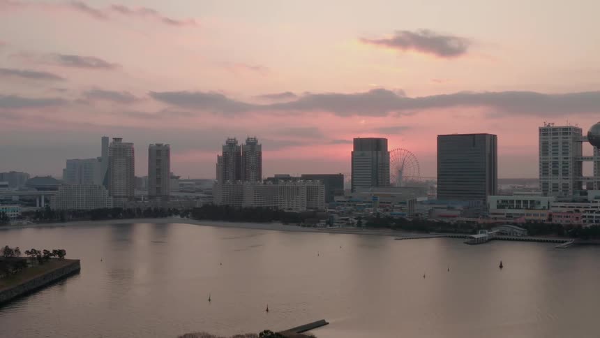Aerial view of skyscrapers and ferris wheelnext to river at sunset