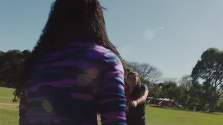 Group of young women practicing australian football on a field in the city