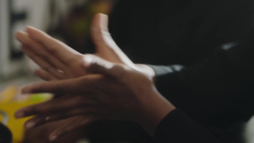 A person molds dough in their hands while cooking in a kitchen next to another person