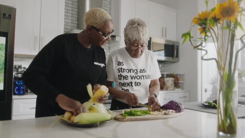A pair of women cook together in a home kitchen during the day
