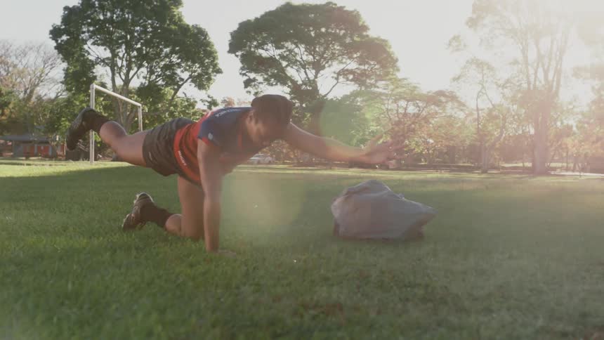 A female athlete does exercises on an athletics field during the day