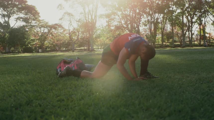 A female rugby player does leg stretches in a field