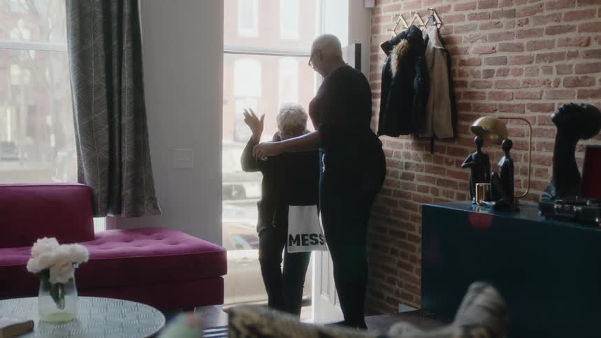A woman enters the home and hugs a friend