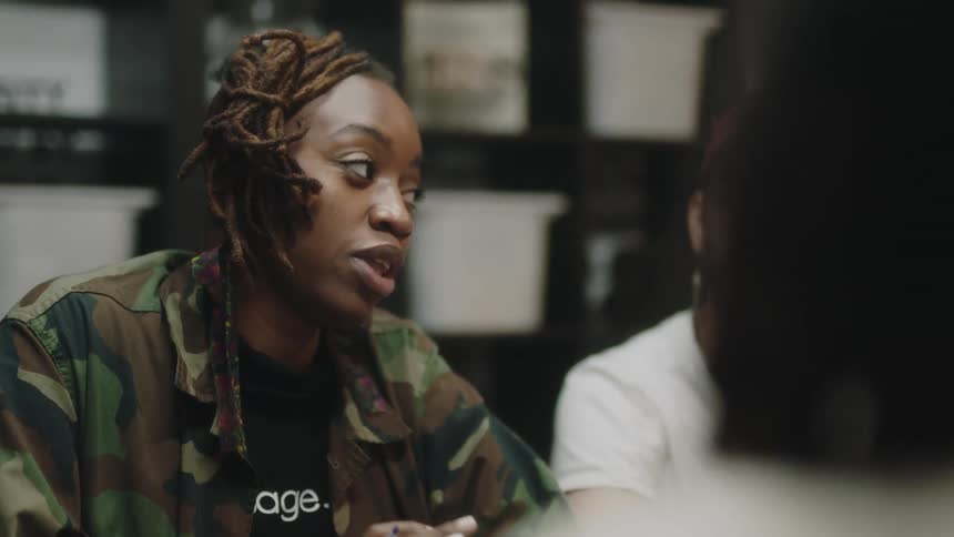 A woman laughs while talking to the people sitting with her around a table indoors