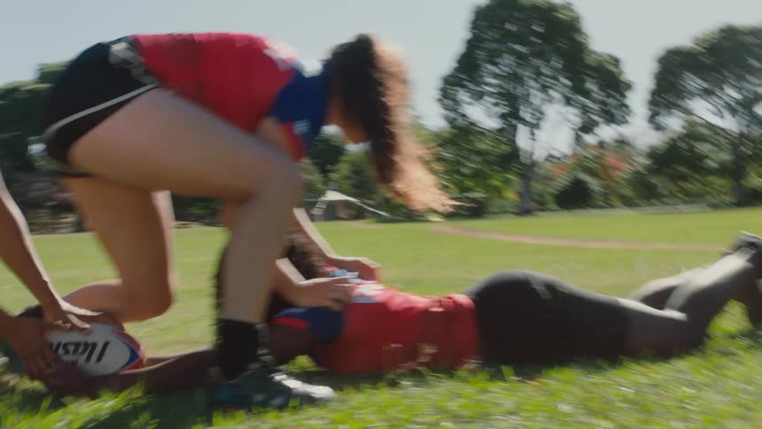 Group of strong girls energetically playing football on a field at daytime