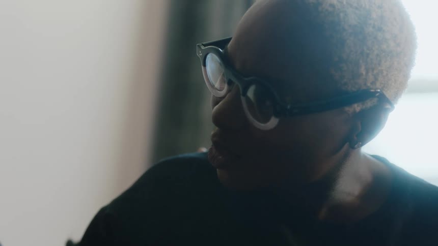 Young happy woman wearing glasses sits at home talking to someone