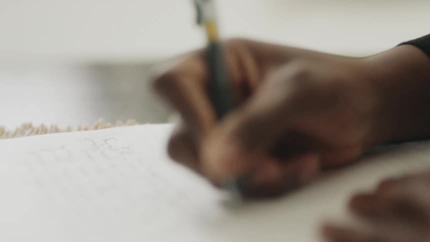 A woman is writing on a sheet of paper with a pen
