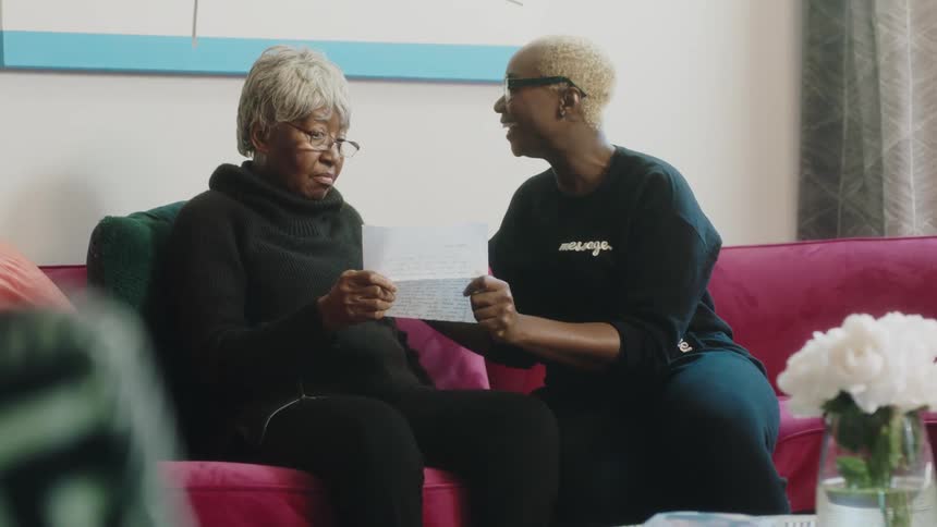 Happy mother and daughter sitting on a couch at home hugging each other