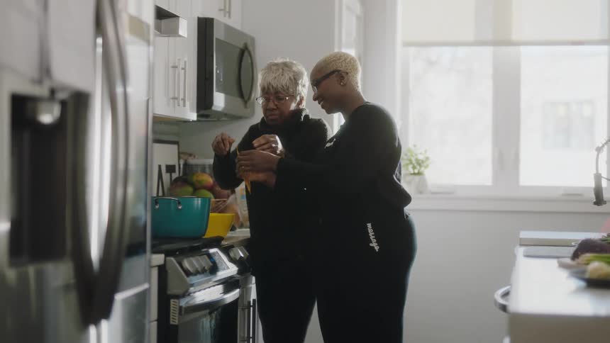 Woman and older relative cook together in kitchen