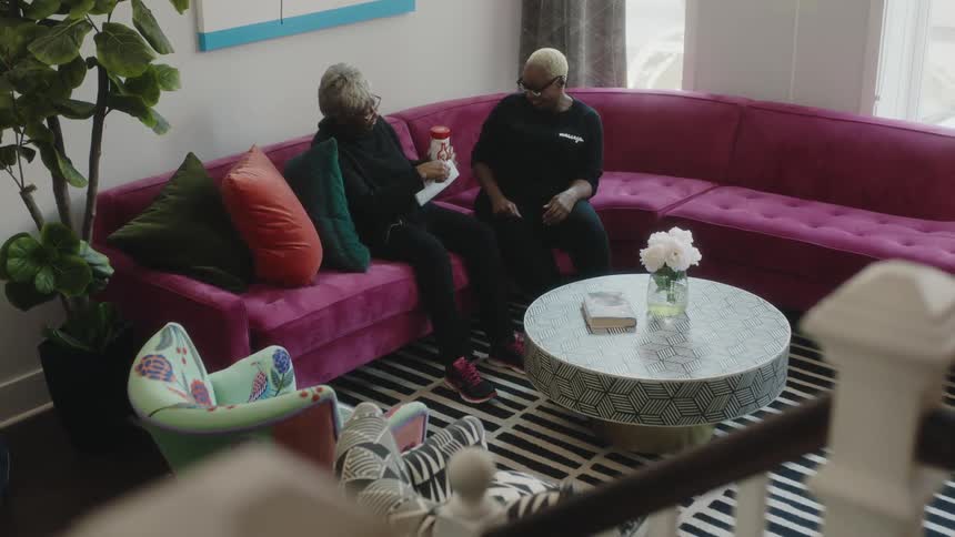 Happy mother and daughter sitting on a couch at home talking to each other