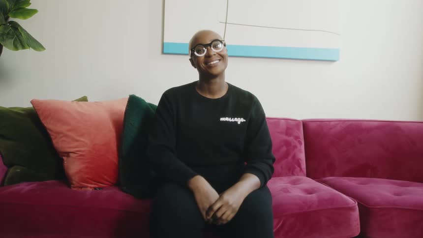 Woman sits on brightly colored sofa smiling