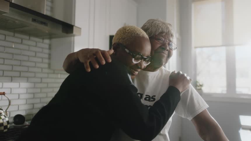Happy mother and daughter talking and hugging in the kitchen at home
