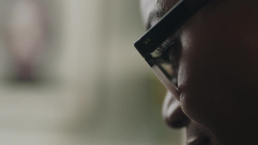 Close up of the face of a woman wearing glasses sitting at home